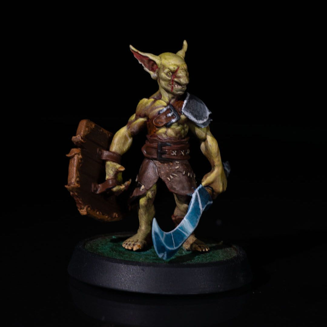 Painted 32mm Goblin Fighter miniature wielding a jagged sword and wooden shield, posed for battle in vivid greens and browns.