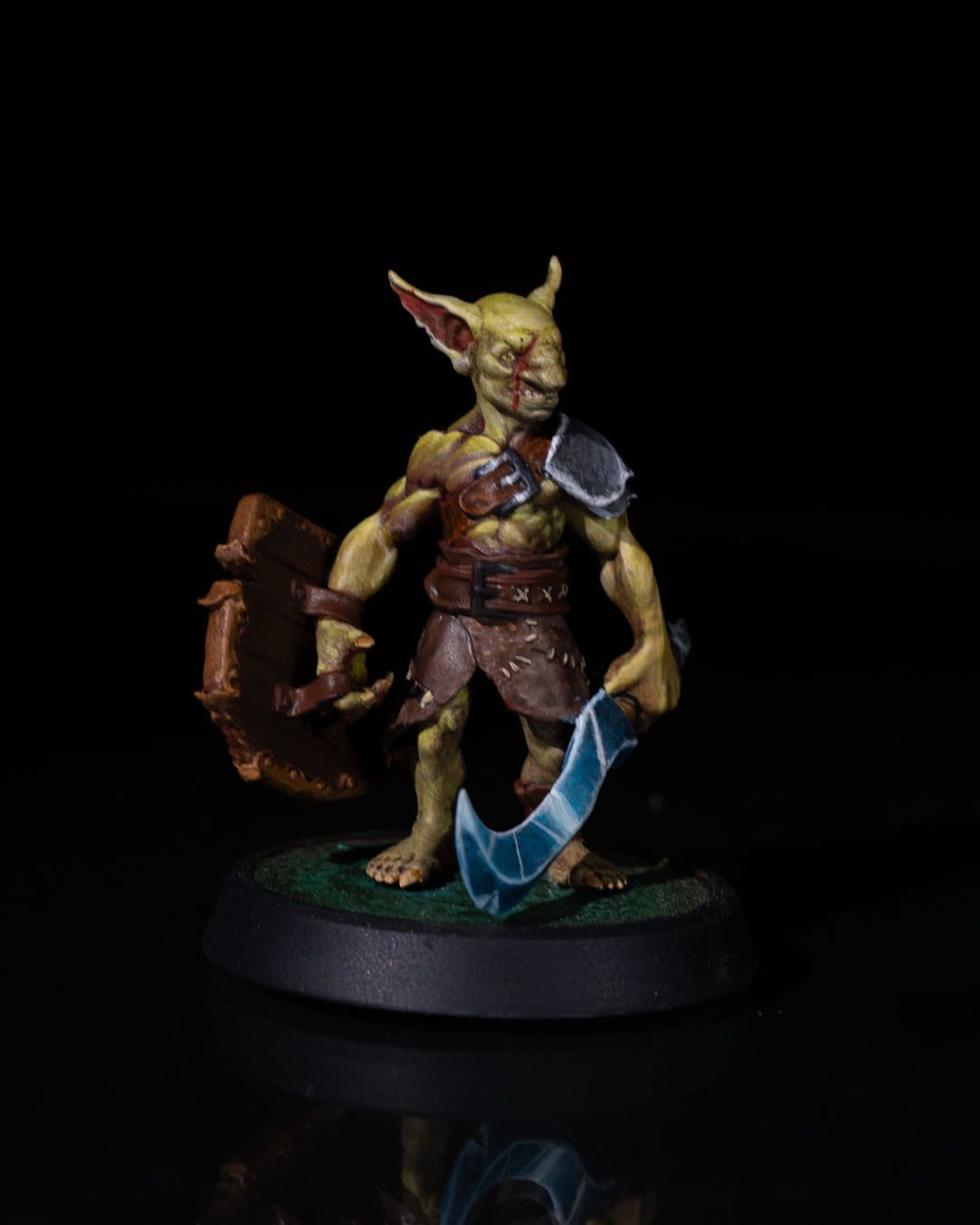 Painted 32mm Goblin Fighter miniature wielding a jagged sword and wooden shield, posed for battle in vivid greens and browns.
