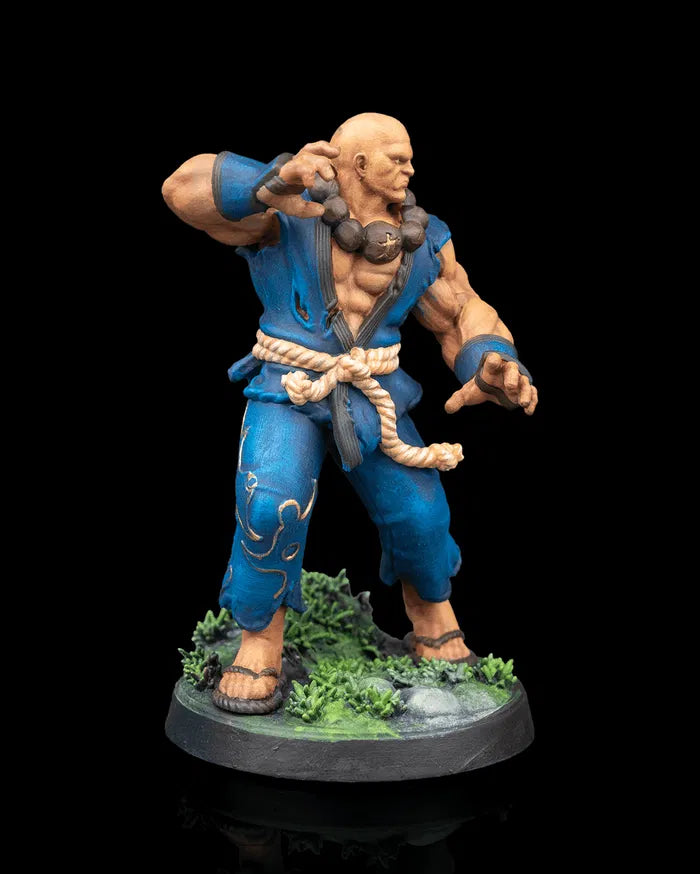 Side angle of the painted Human Monk Stonefist miniature highlighting his bracers, beads, and powerful stance on a rocky, plant covered base.