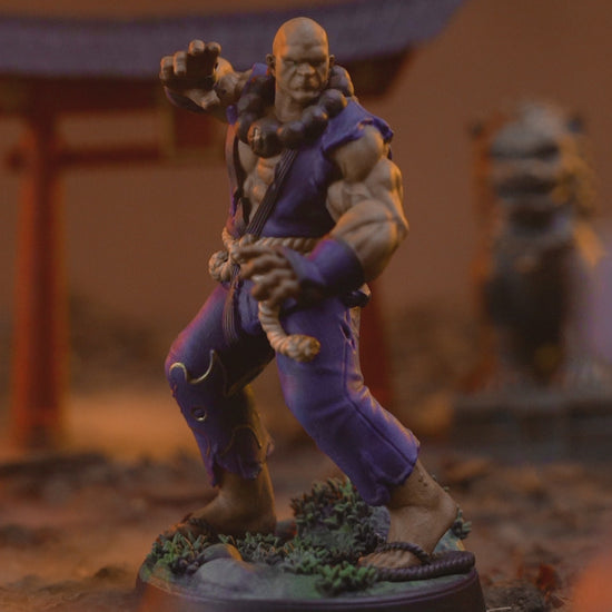 360 degree turntable video of the painted Human Monk Stonefist miniature, rotating to show his blue gi, rope belt, beads, and scenic base from every angle.
